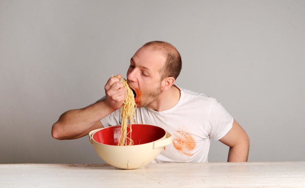 Ritratto fotografico di uomo che mangia gli spaghetti pasta con le mani