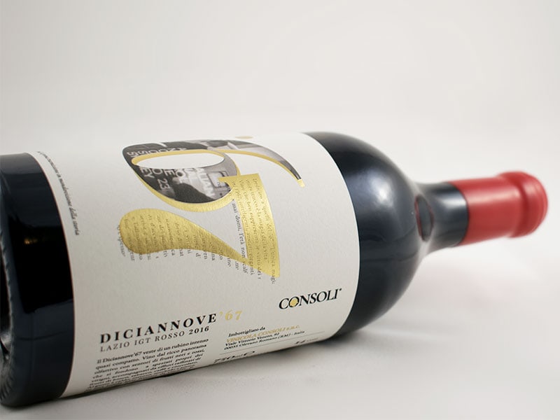 Bottiglia di vino rosso con chiusura del tappo in ceralacca con etichetta in carta bianca decorata in lamina oro e rilievo serigrafico.